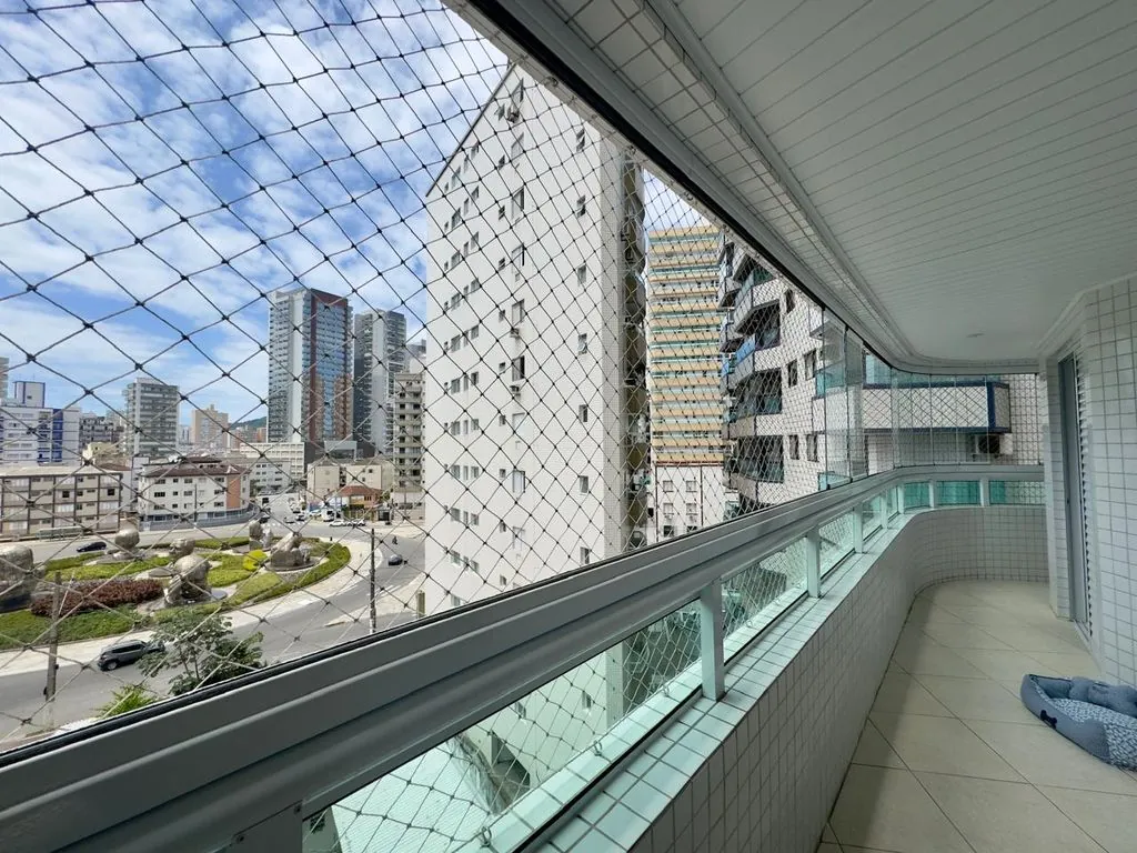 ampla varanda gourmet envidraçada com tela de proteção, churrasqueira a carvão e vista livre para praça